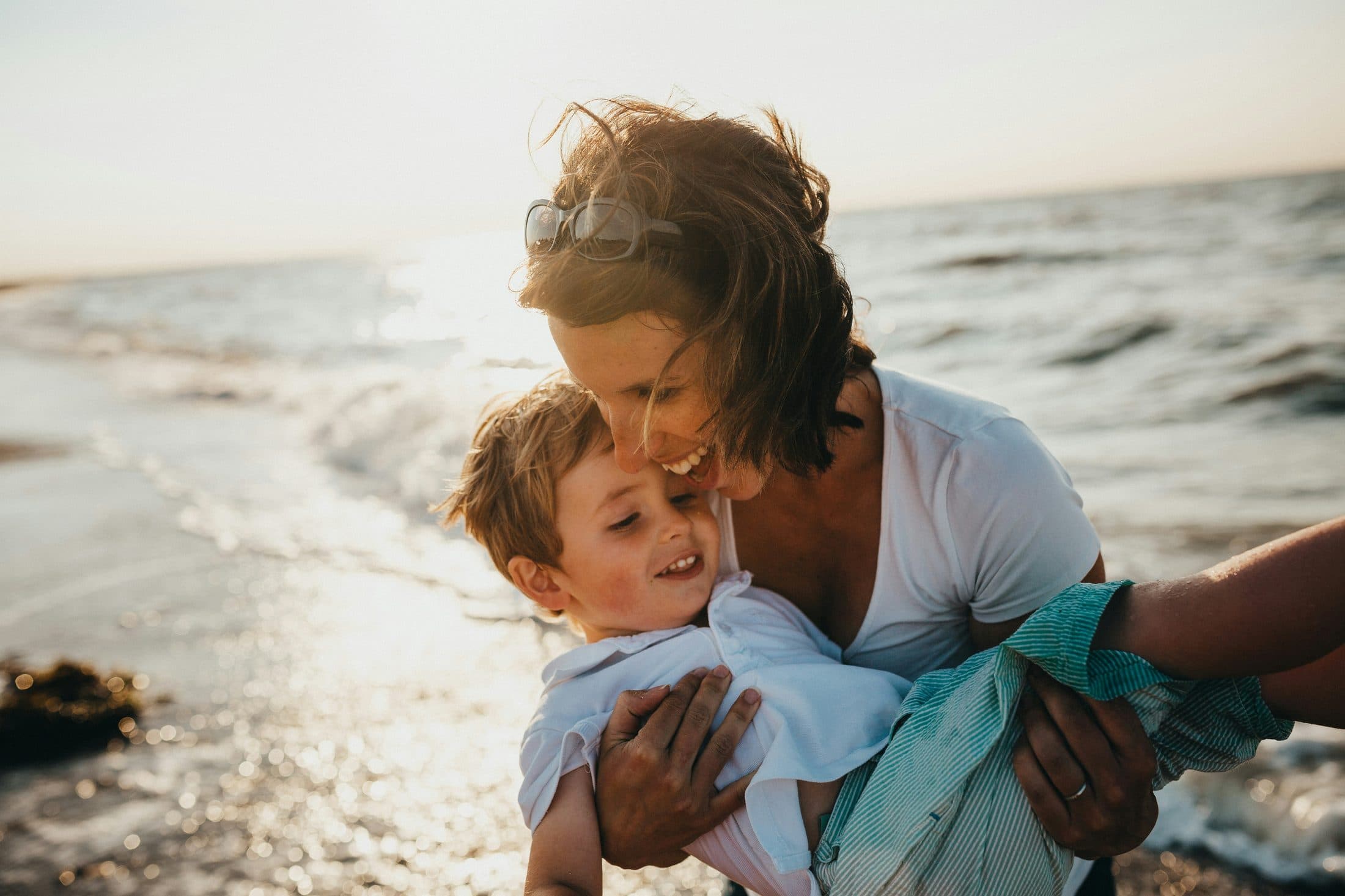 Mother and child walking on a beach at golden hour