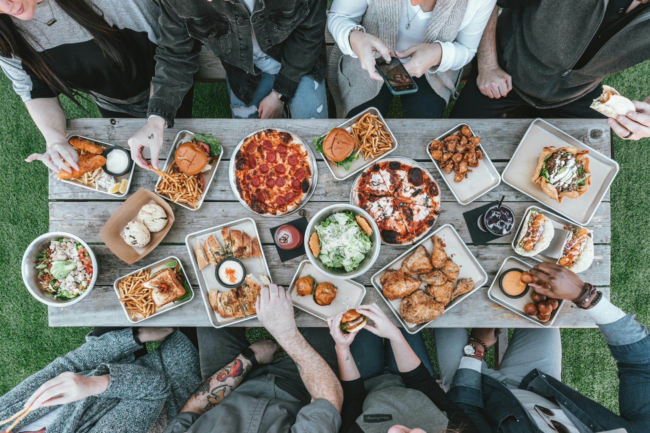 Diverse group sharing an outdoor meal with a wide spread of food